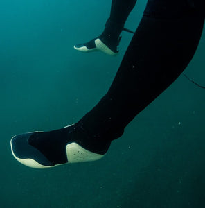 Surfer's feet wearing booties underwater