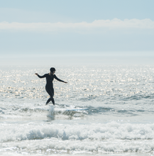 Load image into Gallery viewer, Woman cross stepping on a longboard in a Manera Wetsuit
